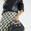 Svart liten totebag med metallhandtag och berlock
