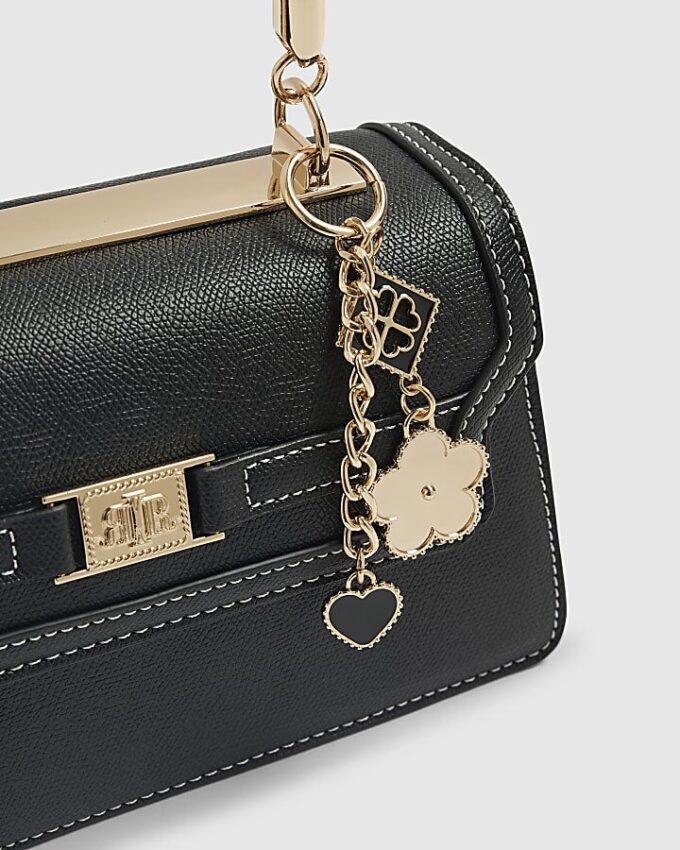 Svart liten totebag med metallhandtag och berlock